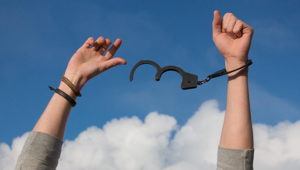 Foto mostrando mãos com algemas abertas sugerindo libertação sobre como se livrar das drogas dos vícios e do álcool