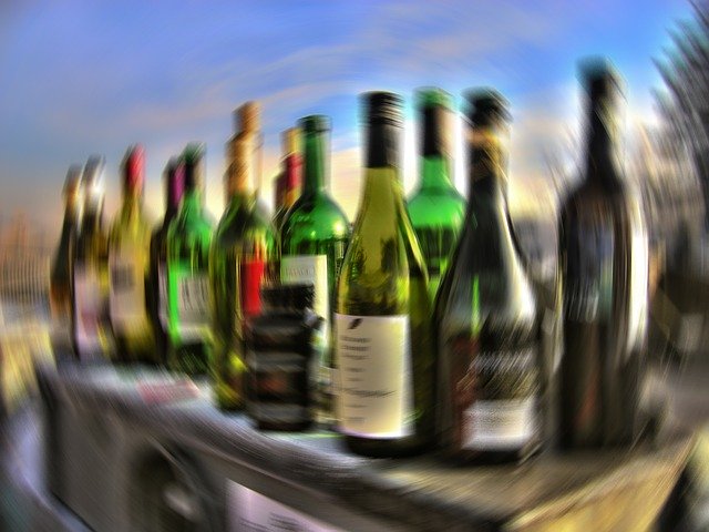 Garrafas de bebidas alcoólicas com imagem destorcida representando embriagues e dependência químca